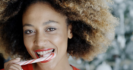 Image showing Young woman biting a festive candy cane