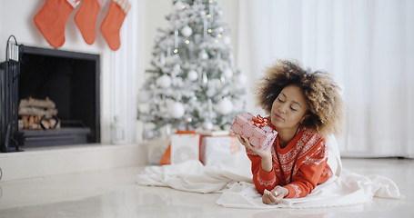 Image showing Young African girl lying looking at her Xmas gift