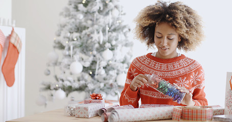 Image showing Attractive young woman wrapping Christmas gifts