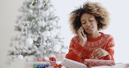 Image showing Young African woman wrapping gifts at Christmas