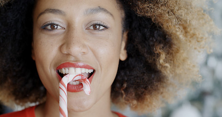 Image showing Fun young woman biting Christmas candy cane