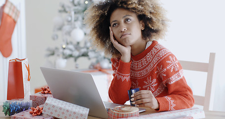 Image showing Young woman pondering over an online purchase