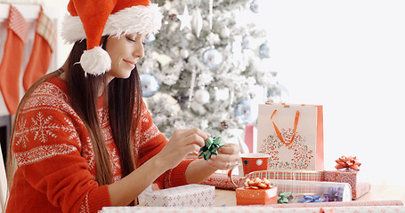 Image showing Young woman sitting wrapping Christmas gifts