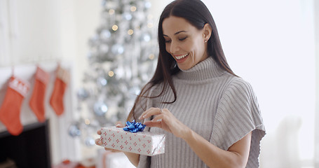 Image showing Smiling young woman opening a Christmas present