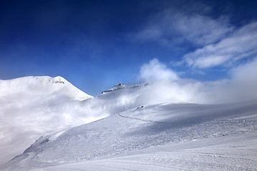 Image showing Ski slope with snowmobile trail and mountains in mist at nice da