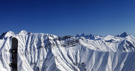 Image showing Panoramic view on snowy mountains and snowboard
