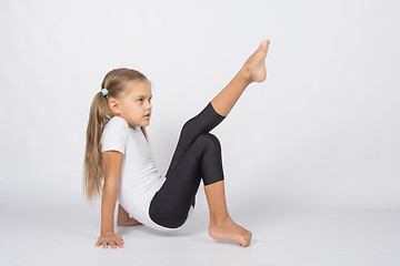 Image showing An aspiring gymnast trying to pull his left foot resting on the hands and fingers of the right foot