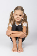 Image showing Girl gymnast sitting on the floor hugging his legs