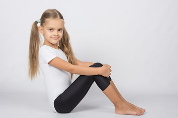 Image showing Gymnast six years sitting hugging her knees legs