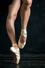 Image showing Close-up ballerina\'s legs in pointes on the black wooden floor 