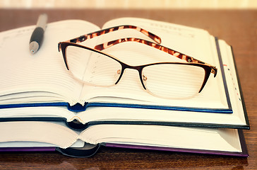 Image showing Glasses, books and notebook on the table surface.