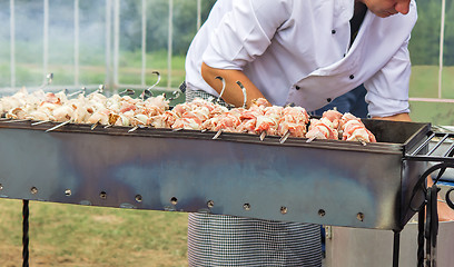 Image showing People at work: a man grilling shashlik on the grill.