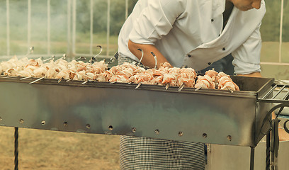 Image showing People at work: a man grilling shashlik on the grill.