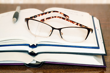 Image showing Glasses, books and notebook on the table surface.