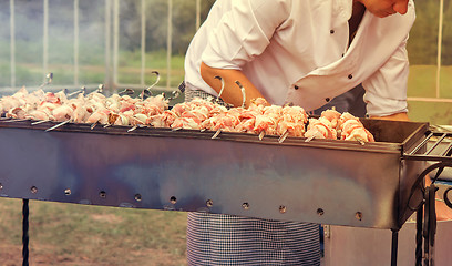 Image showing People at work: a man grilling shashlik on the grill.