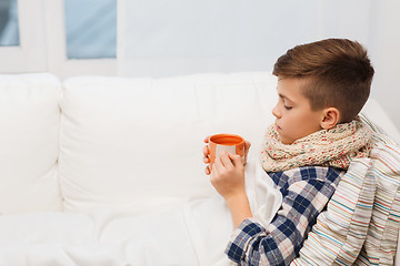 Image showing ill boy with flu in scarf drinking tea at home