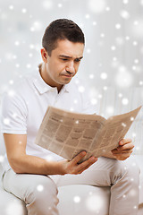 Image showing sad man reading newspaper at home