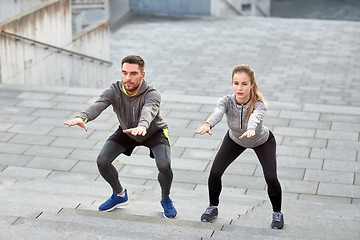 Image showing couple doing squats and exercising outdoors