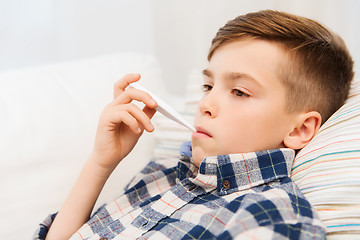 Image showing ill boy with flu and thermometer at home