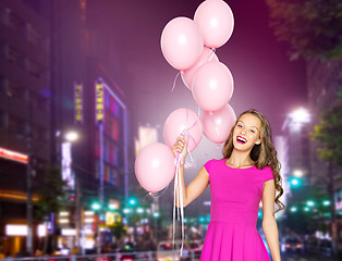 Image showing happy young woman with balloons over night city