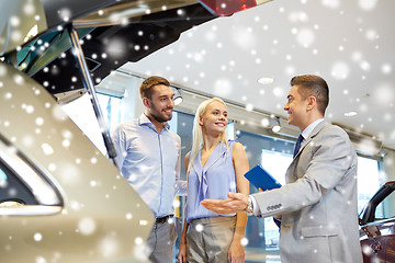 Image showing happy couple with car dealer in auto show or salon