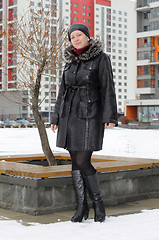 Image showing The woman in a sheepskin coat costs against new buildings