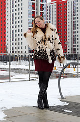 Image showing The woman in a fur coat costs against new buildings