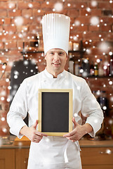 Image showing happy male chef with blank menu board in kitchen