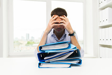 Image showing sad businessman with stack of folders at office