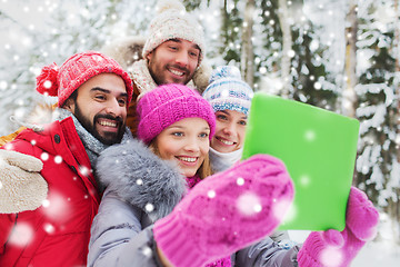 Image showing smiling friends with tablet pc in winter forest