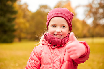 Image showing happy little girl showing thumbs up in autumn park