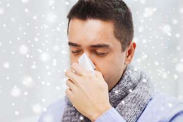 Image showing close up of ill man with flu blowing nose at home