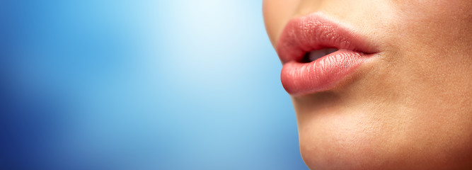 Image showing close up of young woman lips over blue