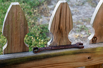 Image showing old rusty wrench on fence