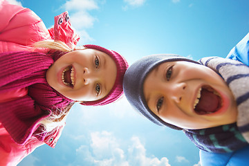 Image showing happy little boy and girl faces over blue sky