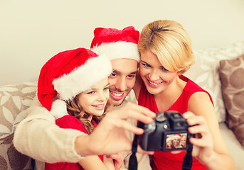 Image showing smiling family in santa helper hats taking picture