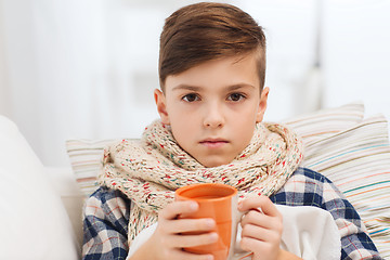 Image showing ill boy with flu in scarf drinking tea at home