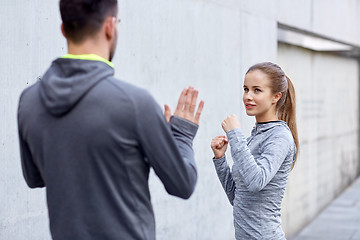 Image showing happy woman with coach working out strike outdoors