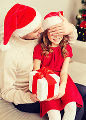 Image showing smiling father surprises daughter with gift box