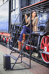 Image showing pretty middle-aged woman with luggage near the old steam locomot