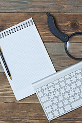 Image showing Computer keyboard, notebook, pen and magnifying glass