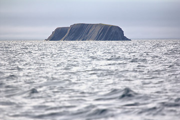 Image showing Layered Rock in sea pierced by waves and wind