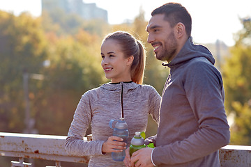 Image showing smiling couple with bottles of water outdoors