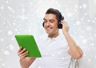 Image showing smiling man with tablet pc and headphones at home