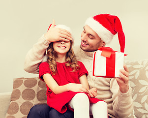 Image showing smiling father surprises daughter with gift box