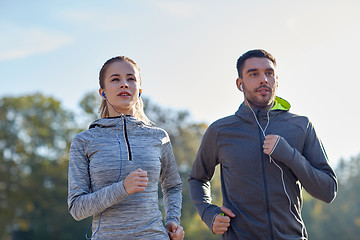 Image showing happy couple with earphones running outdoors