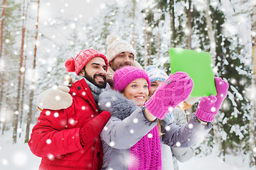 Image showing smiling friends with tablet pc in winter forest