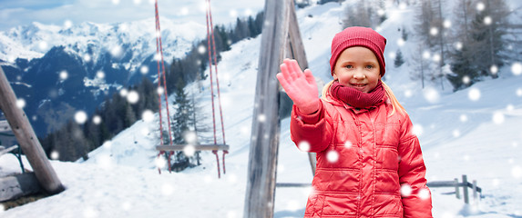 Image showing happy girl waving hand over winter background