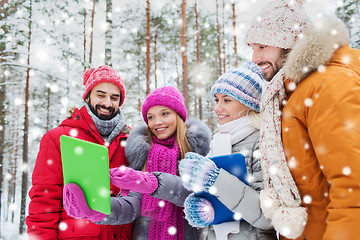 Image showing smiling friends with tablet pc in winter forest