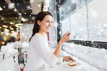 Image showing smiling young woman with cake and coffee at cafe